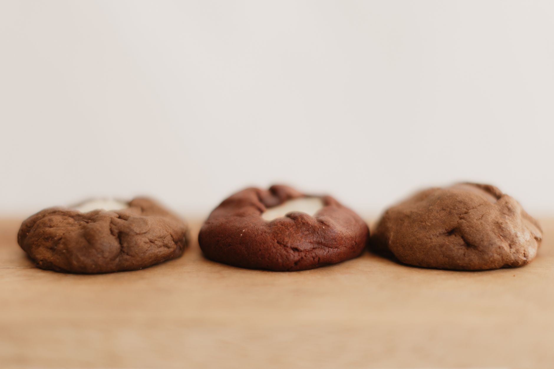 Three thick chocolate cookies with pale filling showing at the top