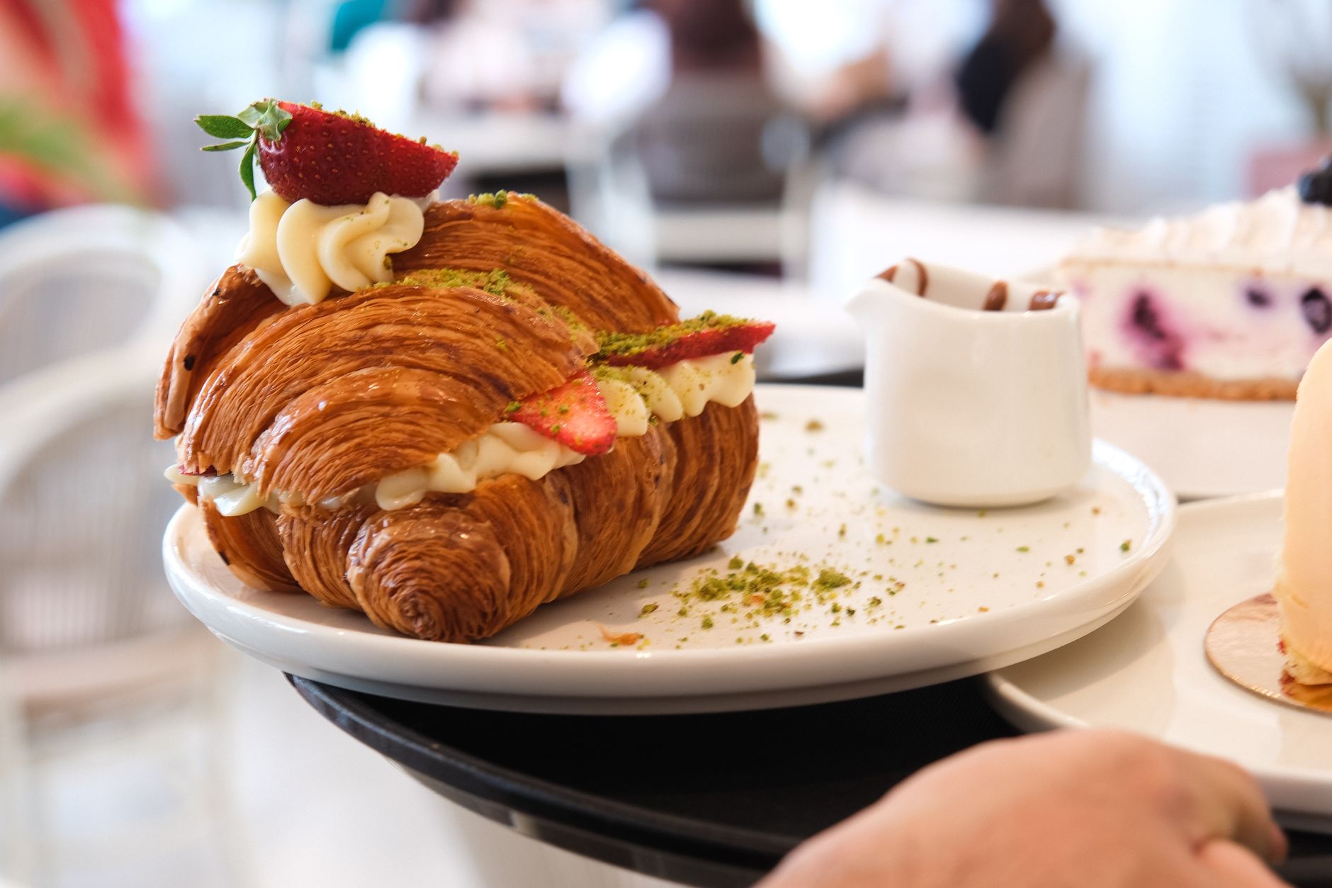 A croissant split and filled with cream and strawberries on a white plate
