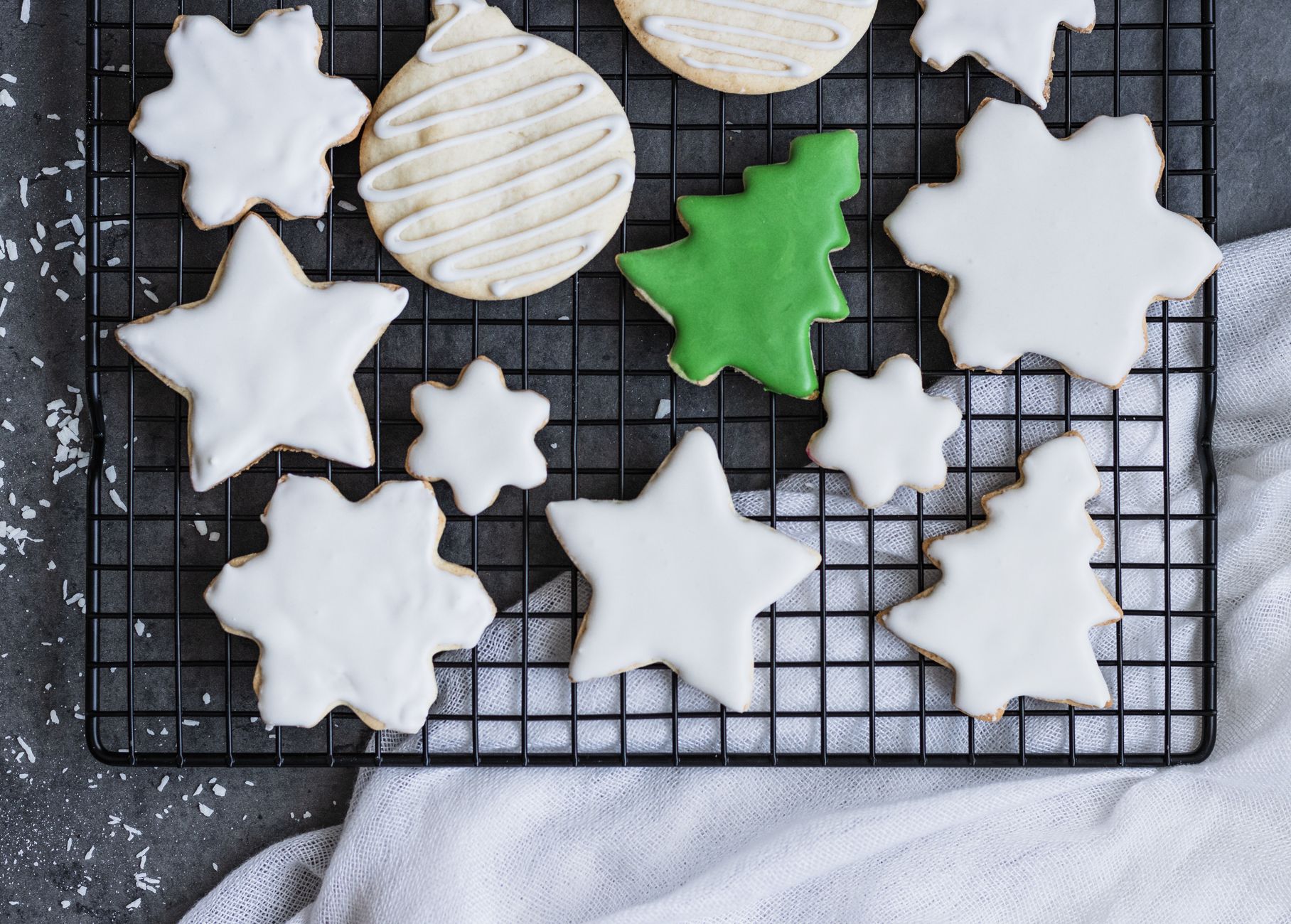 Sugar cookies on a cooling rack with set white icing, one piped in lines