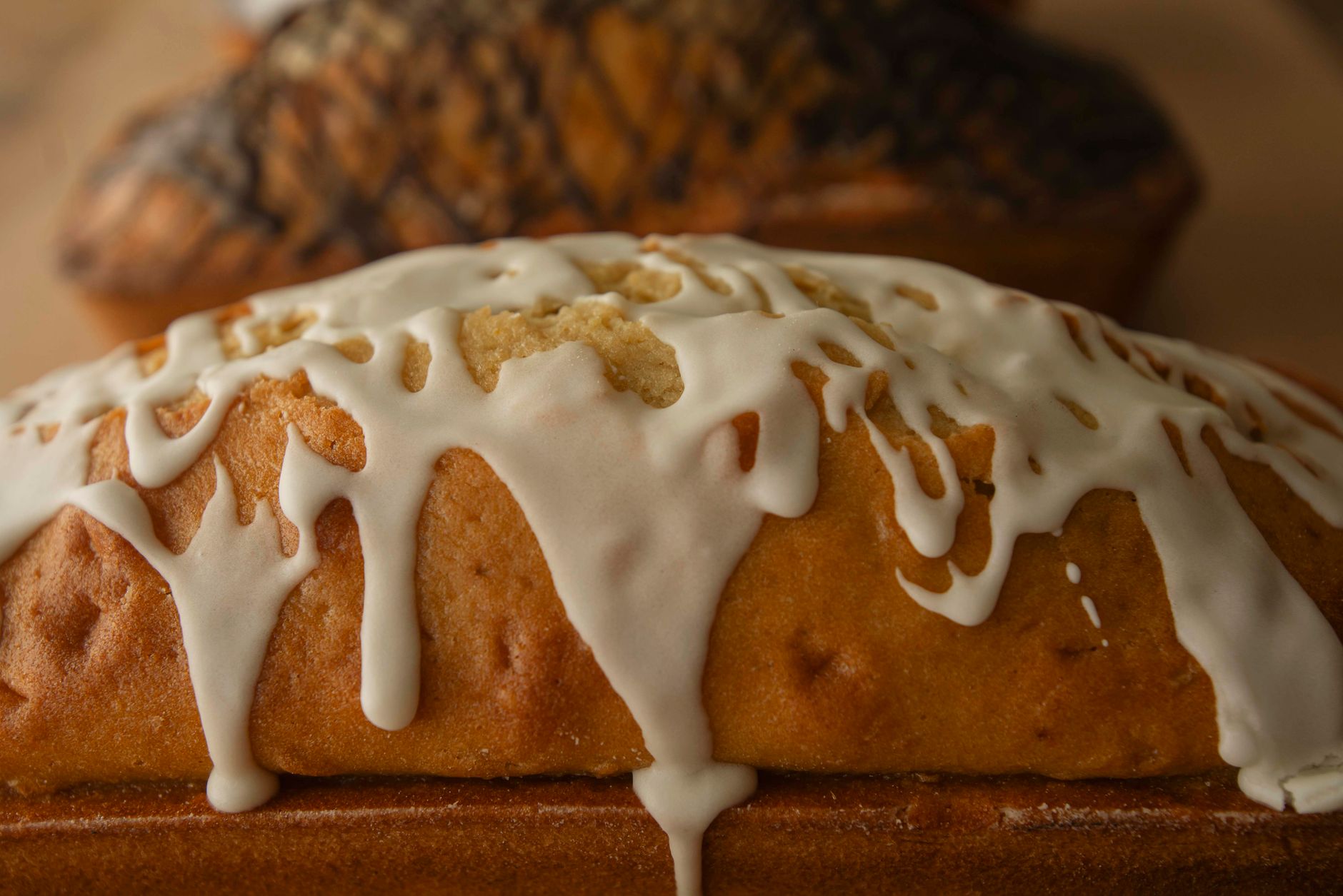 White glaze running down the sides of a golden loaf cake