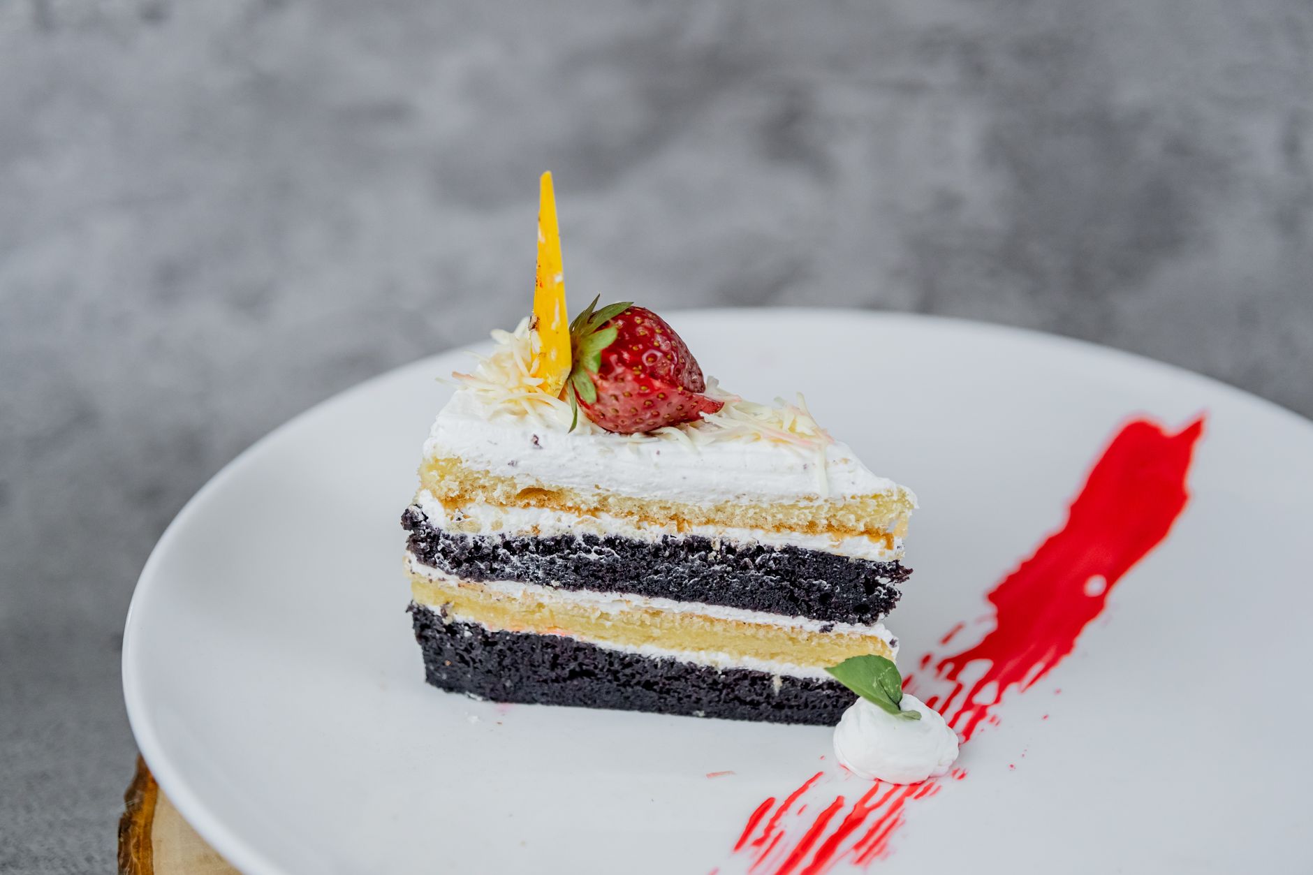A slice of layered cake with cream between the layers on a white plate
